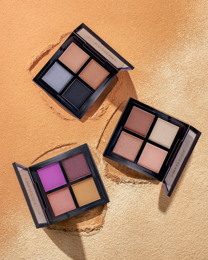 Colorful eyeshadow palettes on a sand-textured backdrop, perfect for beauty and makeup themes.